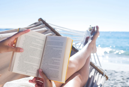 Frau liegt in der Hängematte am Strand und liest