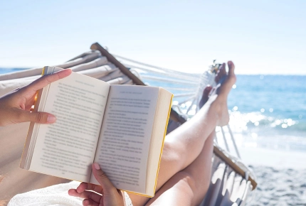 Frau liegt in der Hängematte am Strand und liest