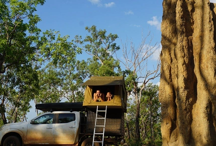 Paar lächelt aus Dachzelt vom Auto
